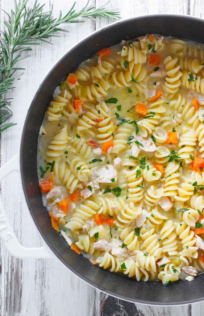 A white Dutch oven filled with Preserved Lemon Chicken Noodle Soup.