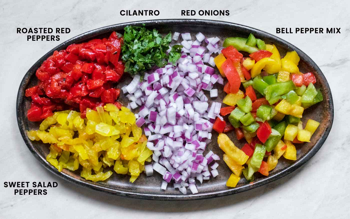 The pasta salad ingredients requiring some prep work arranged on a ceramic brown platter.
