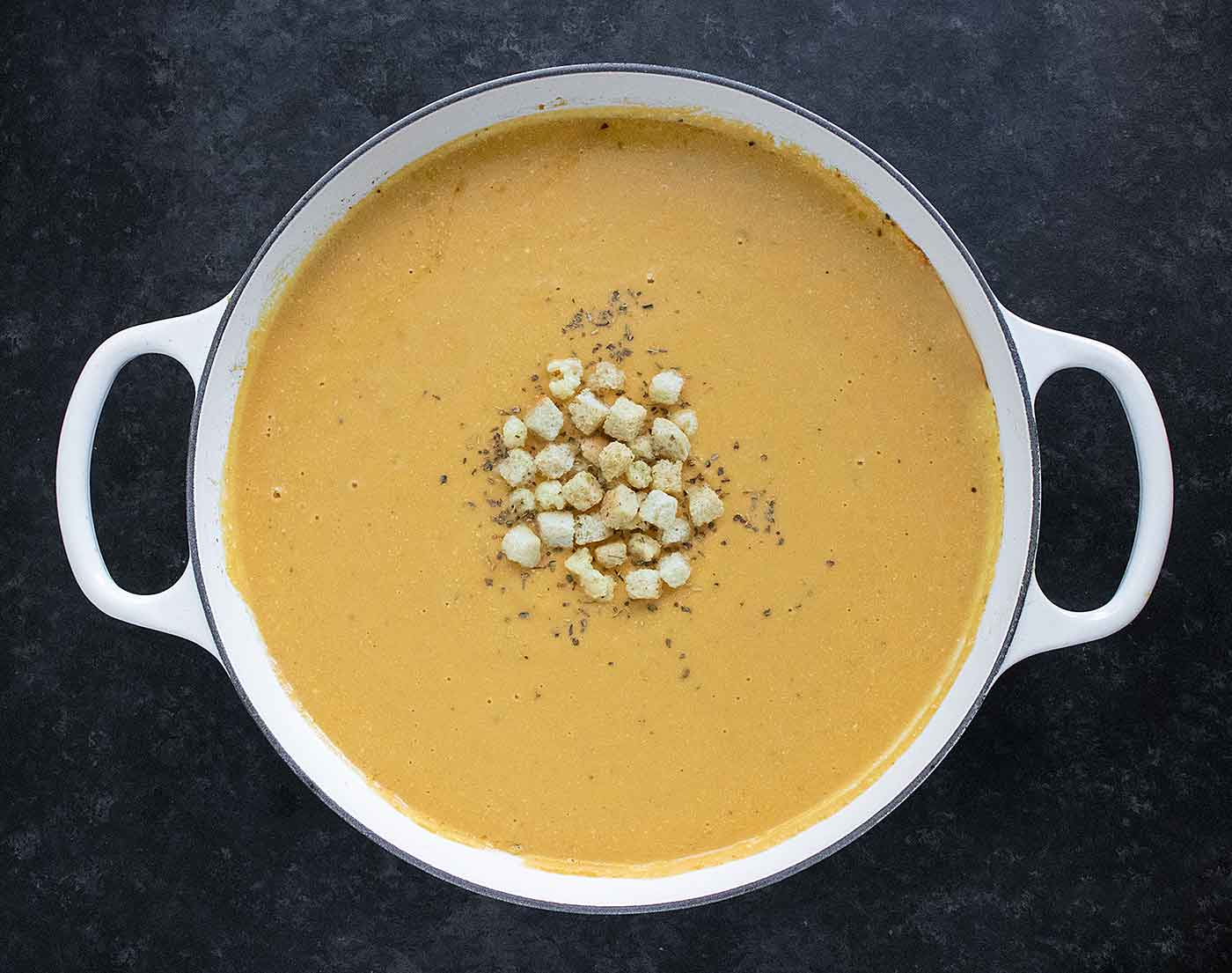 Overhead photo of Roasted Winter Squash and Feta into a large white Dutch oven.