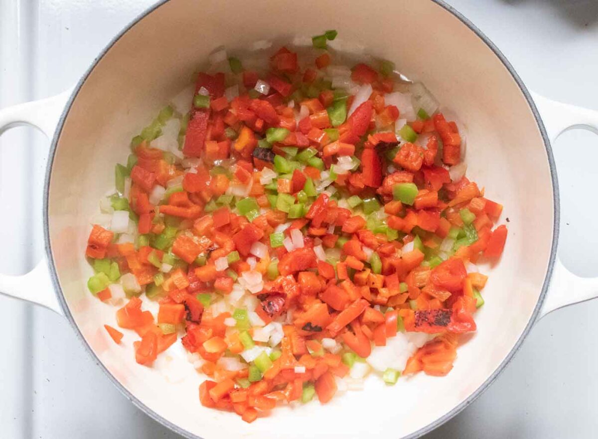 Overhead view of aromatic veggies sauteing in a Dutch oven.