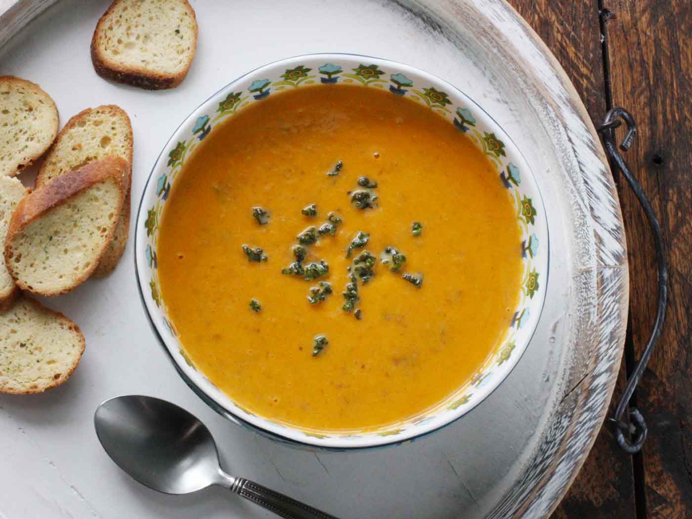 Sweet Potato Sausage Soup in a printed bowl, on a serving tray with bread slices.