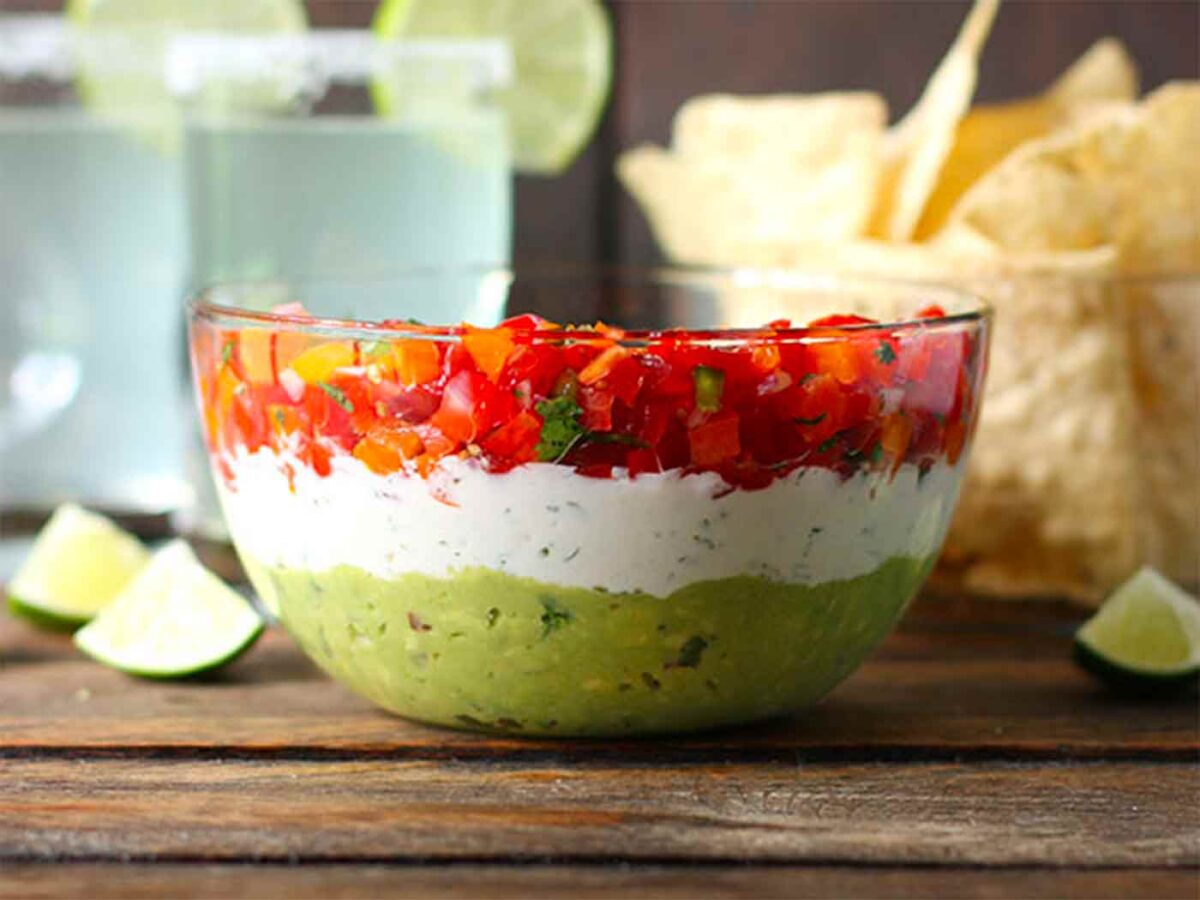 Triple Layer Guacamole Dip in a glass bowl.