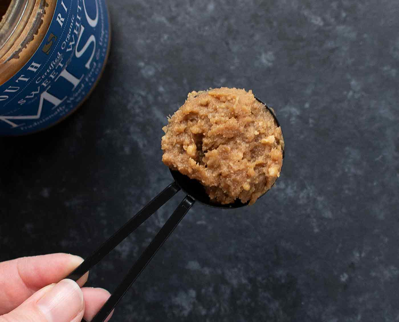 White miso scooped in a black tablespoon.